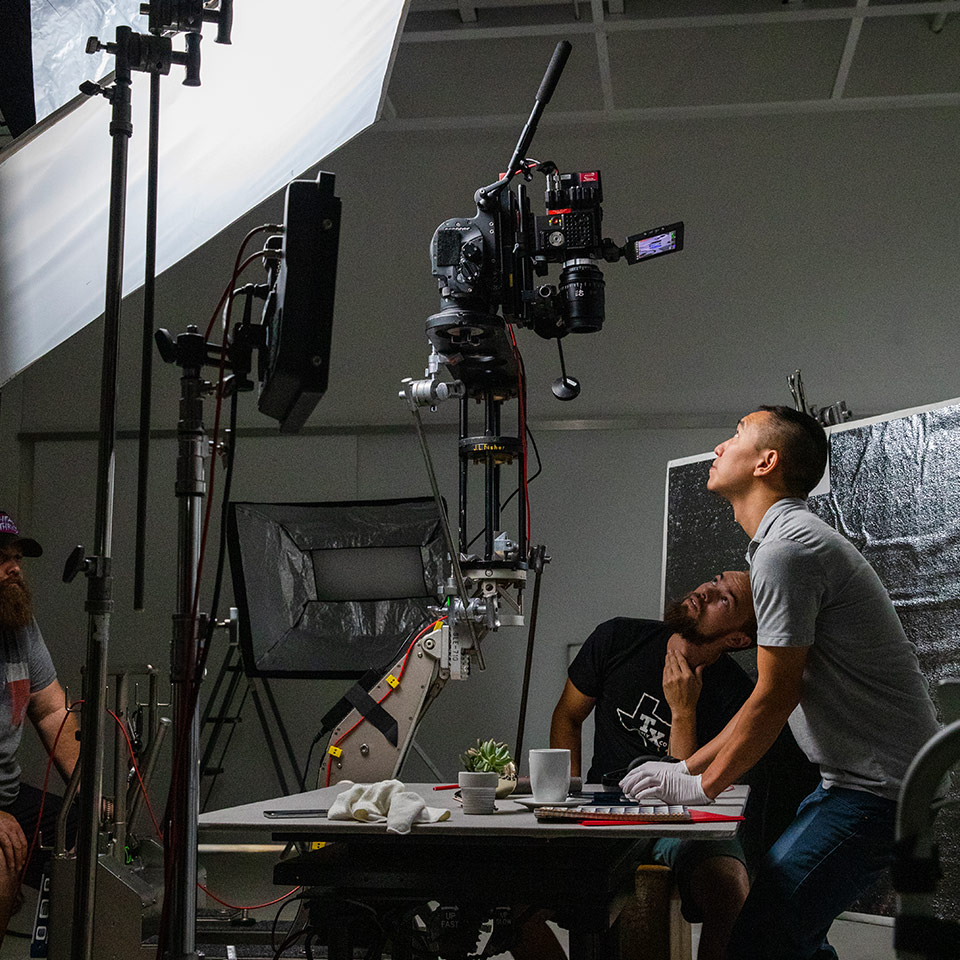 A behind-the-scenes photo of a commercial studio shoot. A Sony Venice is mounted vertically to shoot top down on the table.