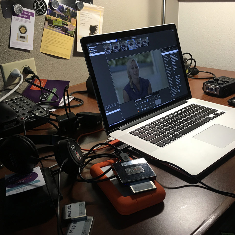 A behind-the-scenes photo of a laptop surrounded by hard drives and video production equipment.