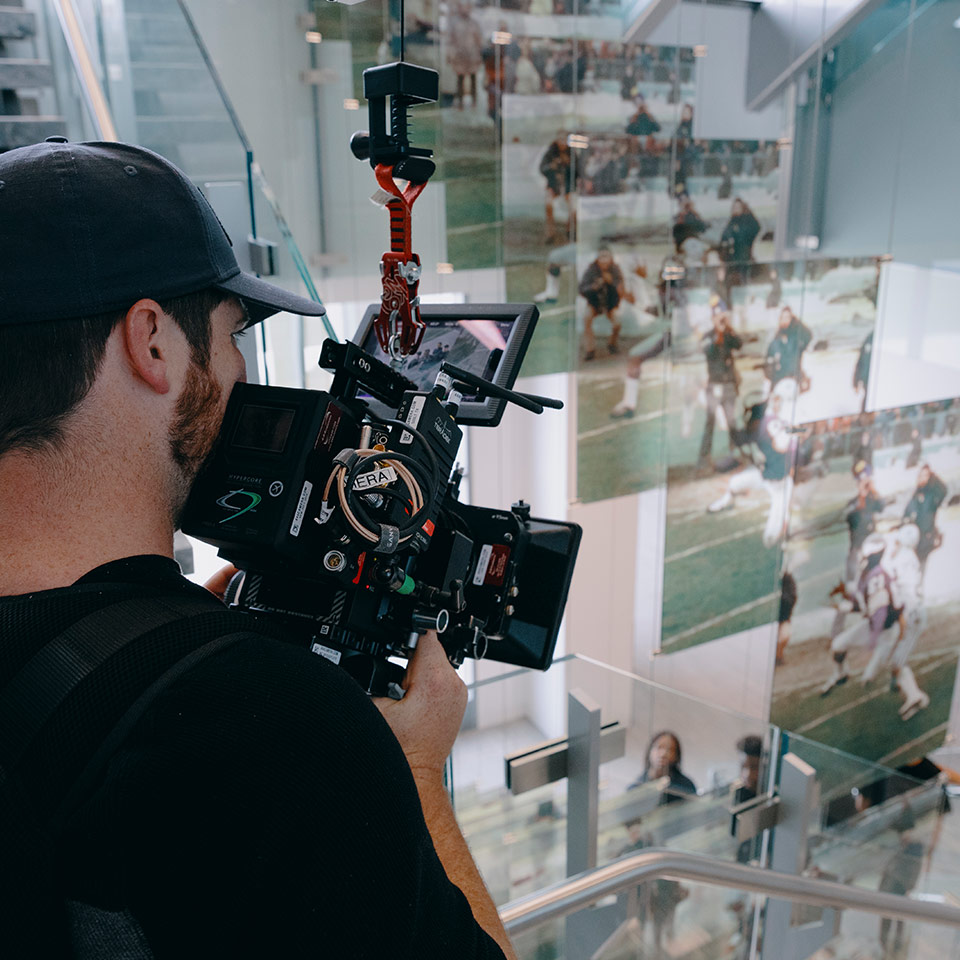 A behind-the-scenes photo of a man holding a cinema camera on an easy rig.