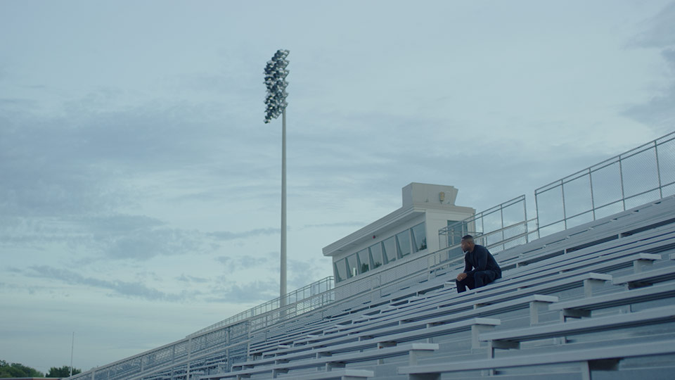 A man sitting in the bleachers of a football stadium.