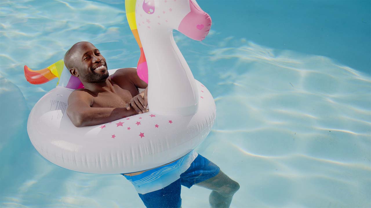 A man in a unicorn poolfloat in the pool.