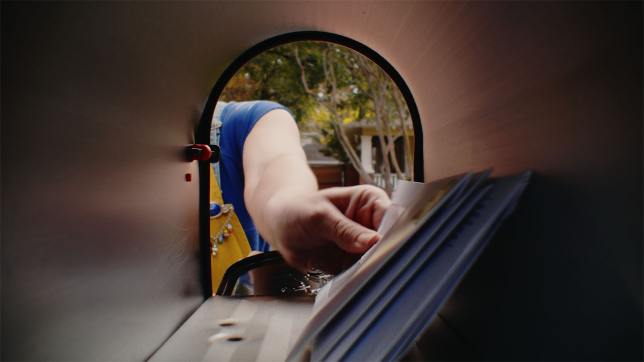A womans hand reaching into a mailbox to retrieve letters.